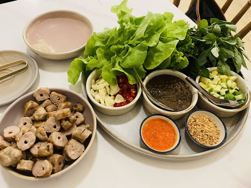 ชุดแหนมเนือง หมูย่างหั่นชิ้นกลม ผักสลัด สมุนไพร และถ้วยน้ำจิ้ม พริก กระเทียม ถั่วลิสง