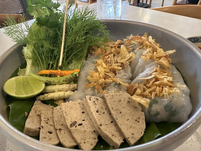 แผ่นแป้งนึ่งโรยหอมเจียว วางคู่หมูยอหั่นแผ่น ผักชีลาว และมะนาวบนใบตอง