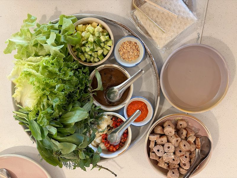 ถาดแหนมเนืองมองจากด้านบน มีผักสด แตงกวา น้ำจิ้ม หมูย่าง และแผ่นแป้งเวียดนาม